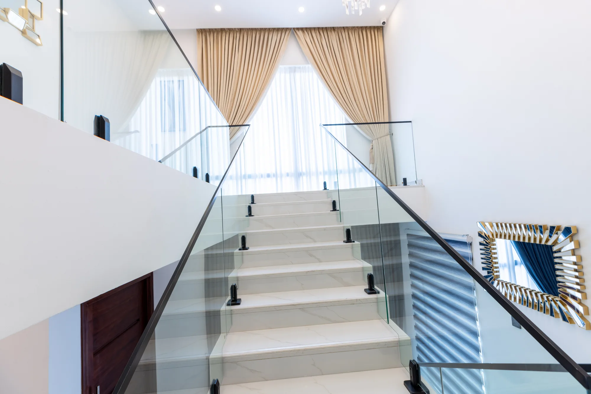 White staircase and glass rail with warm curtain backdrop
